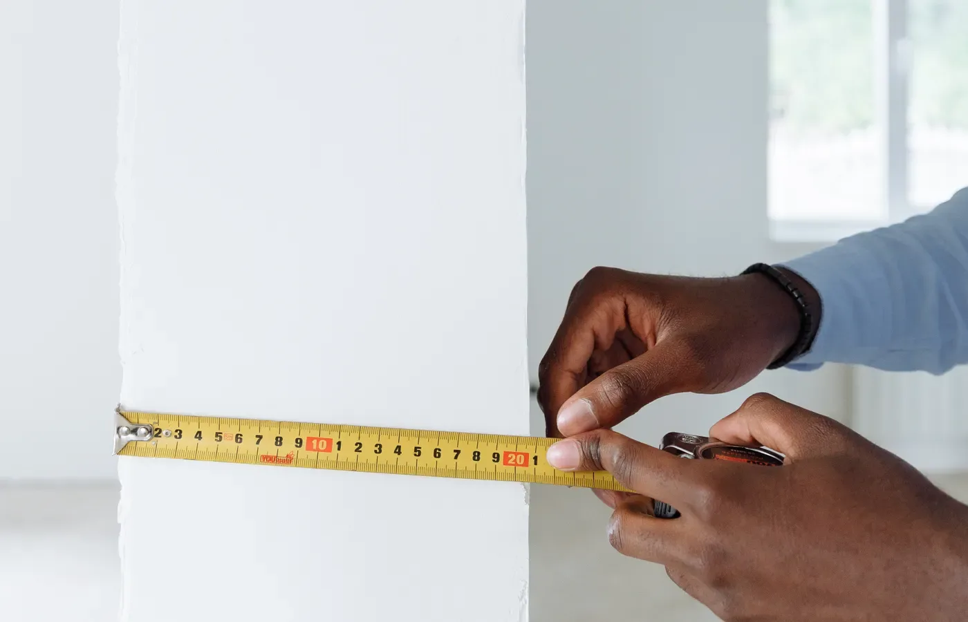 Person checking wall dimensions with a measuring tape during renovation